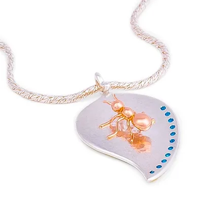 Detailverliebte Schmuckfotografie: Halskette mit Ameisen-Anhänger. Perfekte Inszenierung für Ihre Schmuckkollektion. Detailaufnahme einer silbernen Halskette mit blattförmigem Anhänger, verziert mit einer goldenen Ameise und blauen Steinchen. Exquisite Schmuckfotografie.